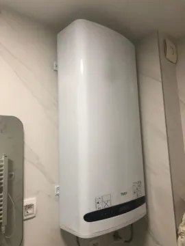A modern electric water heater mounted on a bathroom wall. - image 10