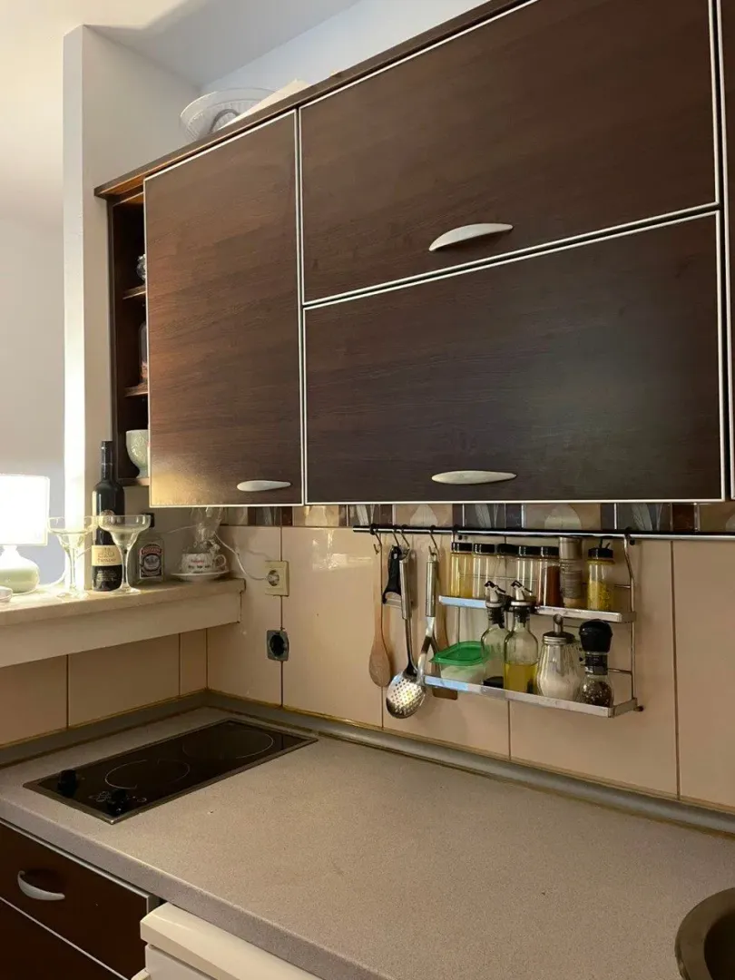 Small kitchen with dark wooden cabinets, a stove, and a spice rack.