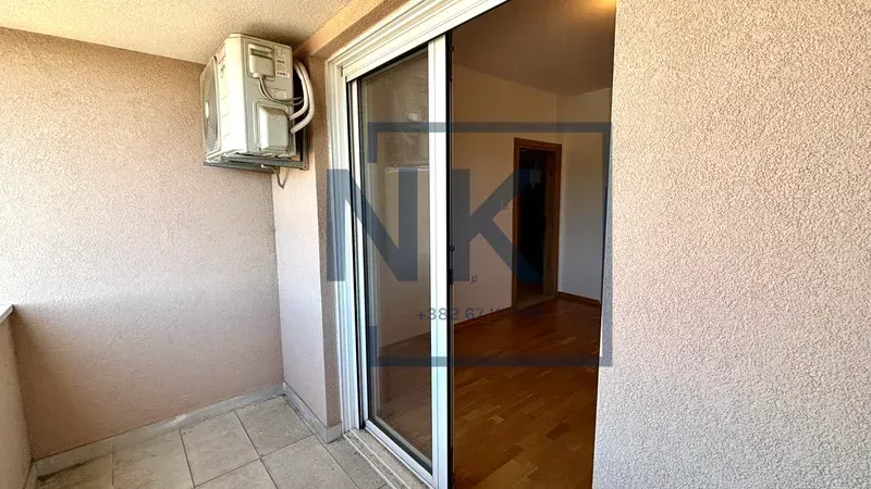 Manji balkon sa klima uređajem i pogledom na unutrašnjost stana kroz klizna vrata.