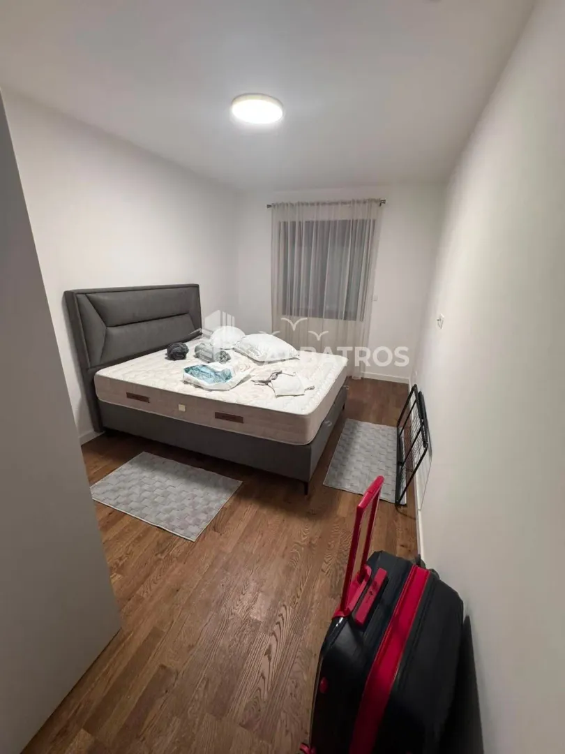 Spavaća soba sa bračnim krevetom i drvenim podom.