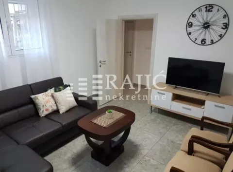 Living room furnished with a sofa, TV, and coffee table. - image 2