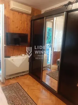 Spavaća soba sa velikim garderoberom, drvenom oblogom na zidu i TV-om. - image 2