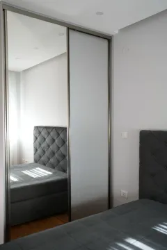 Modern bedroom with a bed and a built-in mirrored wardrobe. - image 6