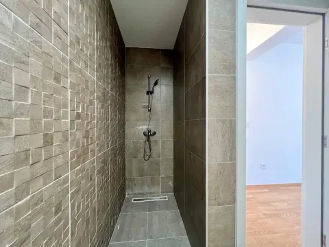 Moderna tuš kabina sa braon pločicama i pogledom na susjednu prostoriju. - image 6