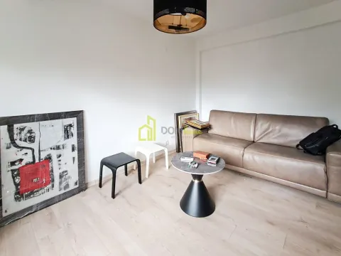 Living room with a beige leather sofa, small coffee table, and paintings on the floor. - image 2