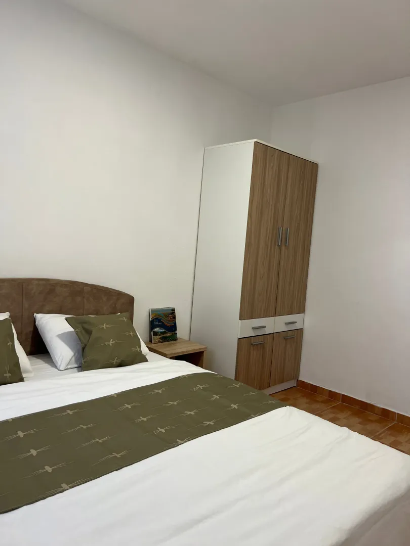 Furnished bedroom with a double bed and a wardrobe.