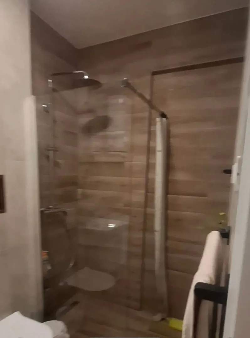 Moderne kupatilo sa tuš kabinom obloženom pločicama u dezenu drveta.