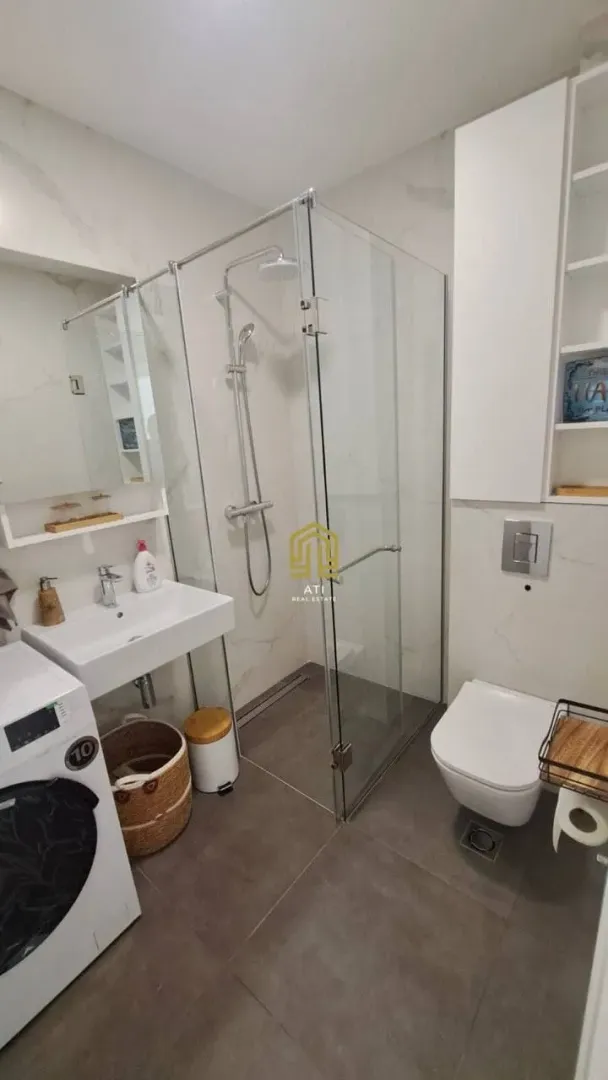 Moderno opremljeno kupatilo sa tuš kabinom, umivaonikom i sanitarijama.