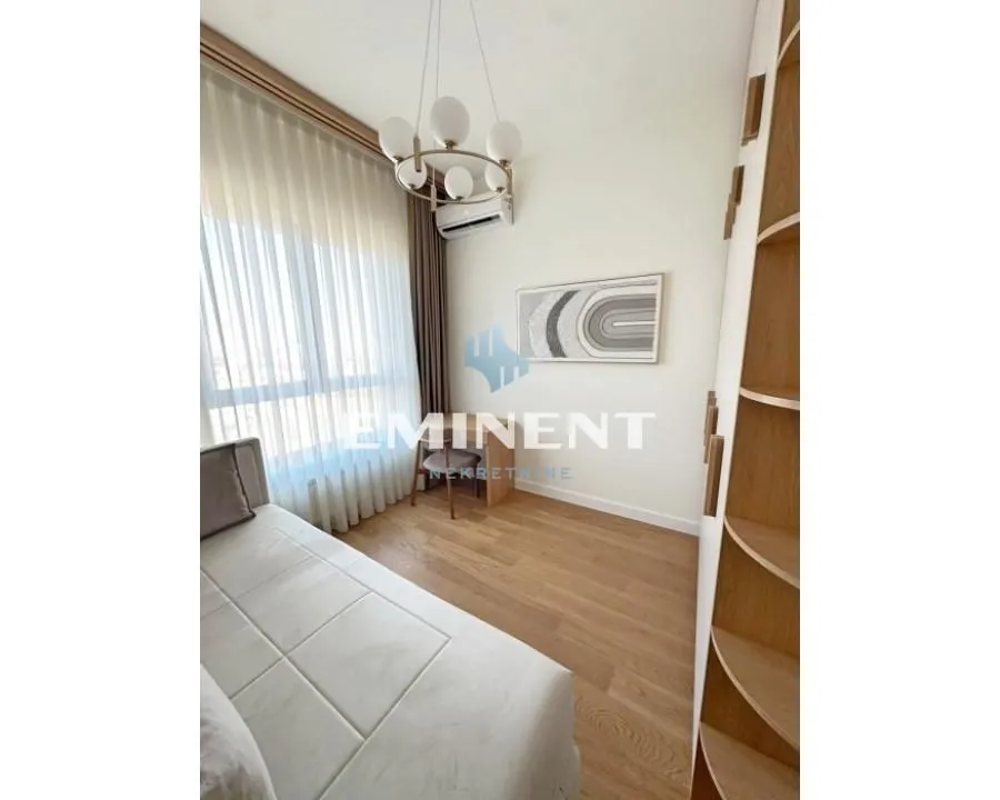 Furnished bedroom with a bed, desk, and shelving units.