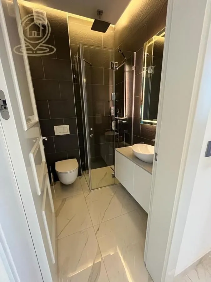 Moderno opremljeno kupatilo sa tuš kabinom, umivaonikom i WC šoljom.