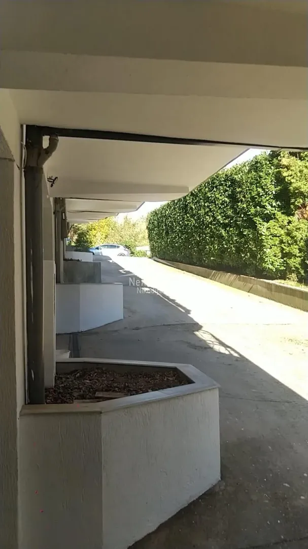 Covered parking space with an access road next to the building.