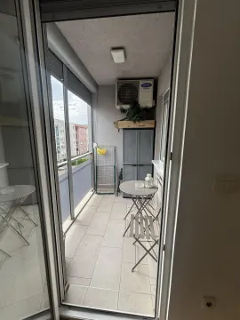 Pogled na zastakljeni balkon sa malim stolom, stolicama i klima uređajem. - image 4