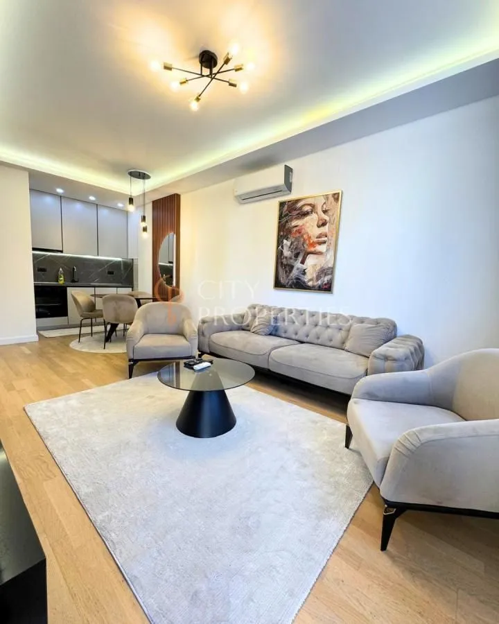 Living room with a sofa, coffee table, and a view of the dining area and kitchen.