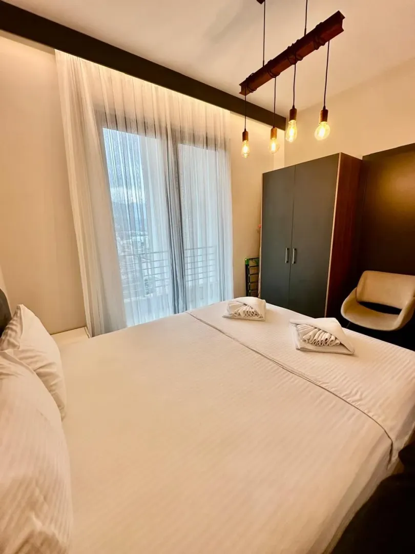 Furnished bedroom with a double bed, wardrobe, and balcony door.