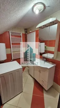 Bathroom with a sink, washing machine, and orange and white tiled walls. - image 12