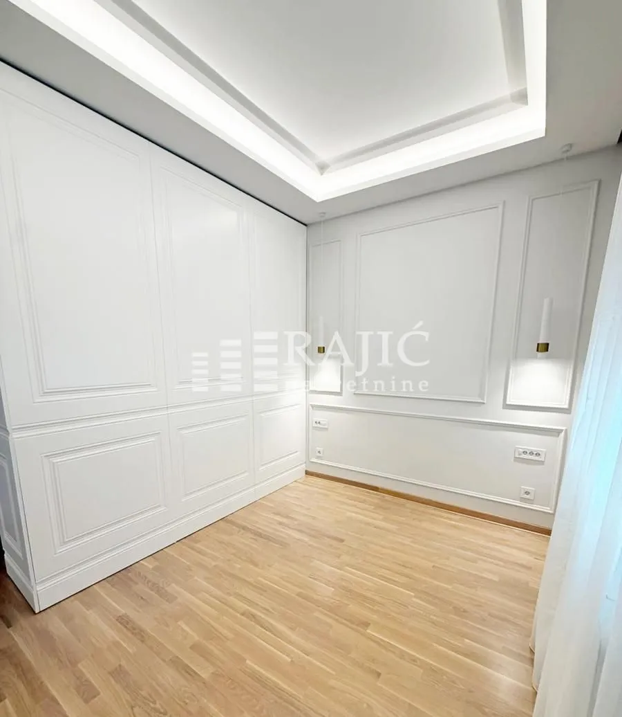 Empty bedroom with a built-in wardrobe and laminate flooring.