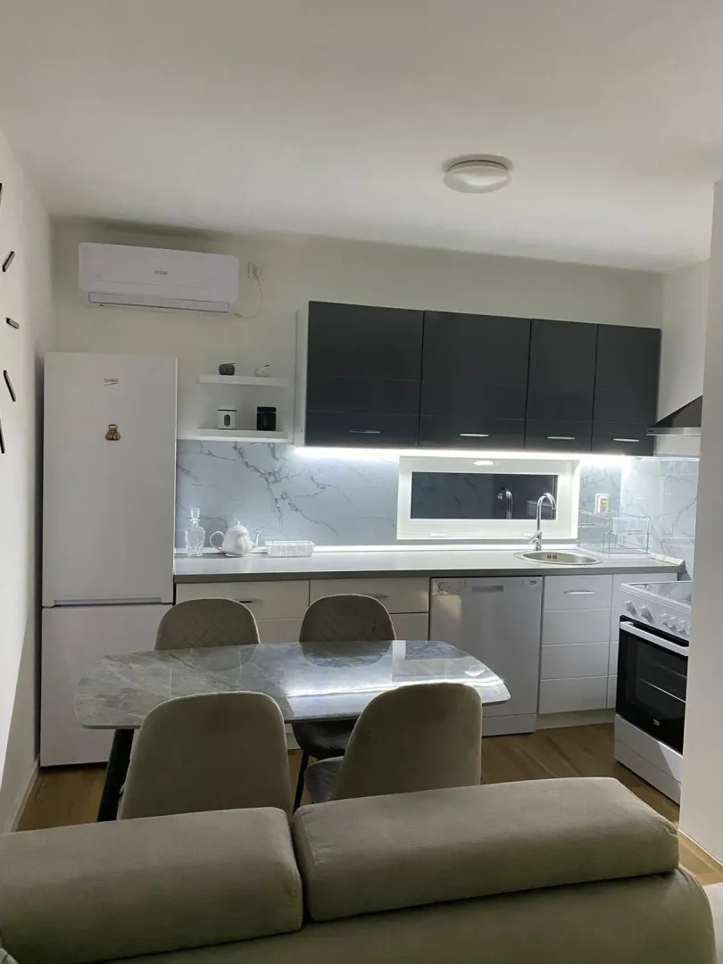 Modern kitchen with dark upper cabinets and white lower cabinets, featuring a dining table with chairs.