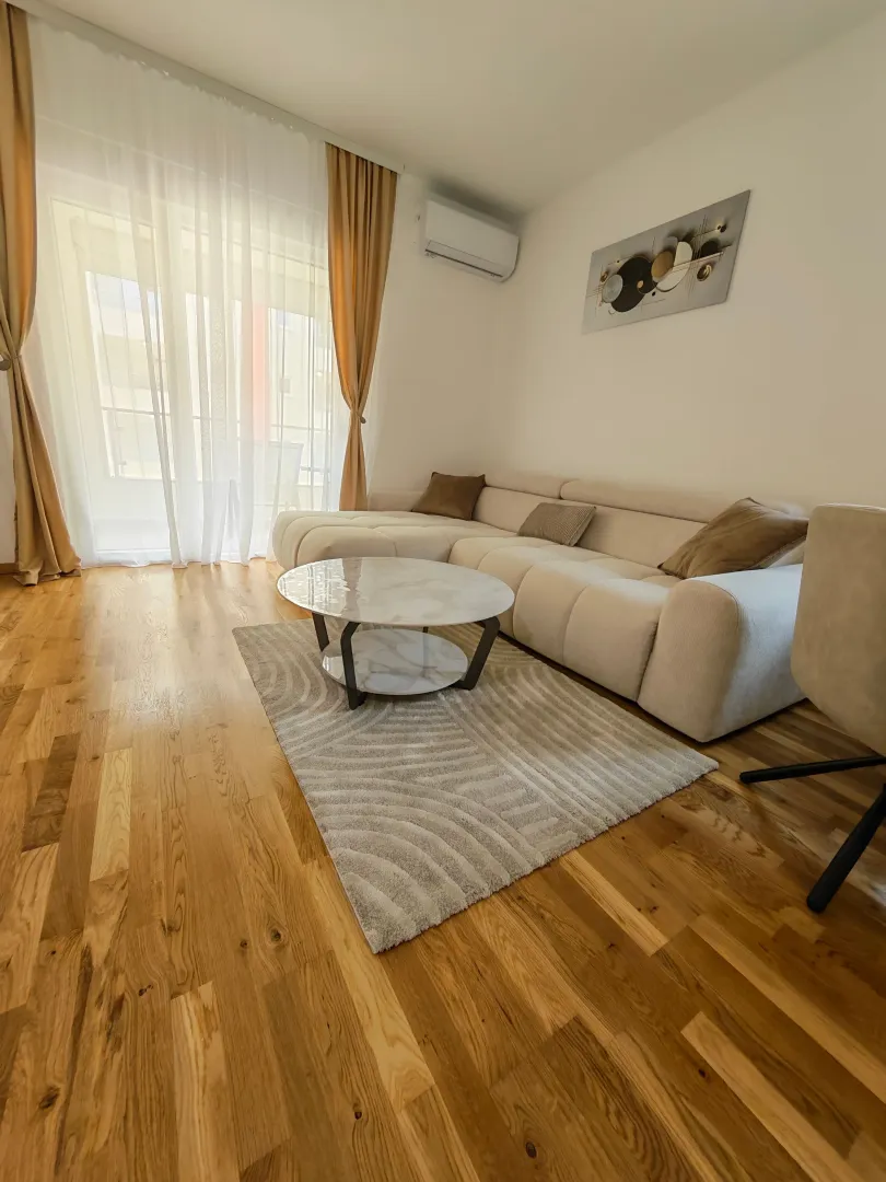 Dnevna soba sa ugaonom garniturom, klub stolićem i izlazom na terasu.