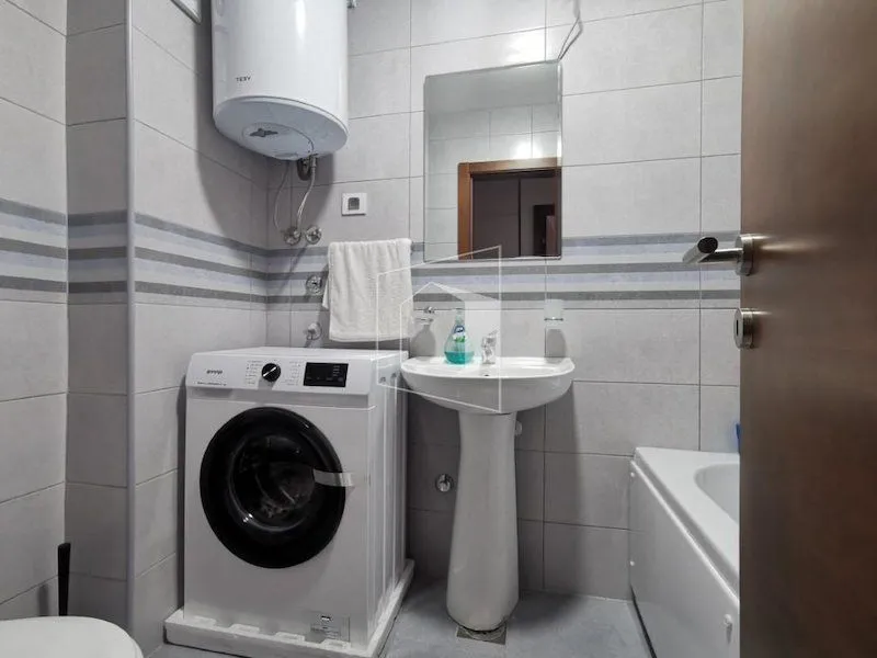 Small bathroom with a sink, shower cabin, washing machine, and water heater.
