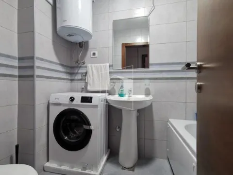 Small bathroom with a sink, shower cabin, washing machine, and water heater. - image 8