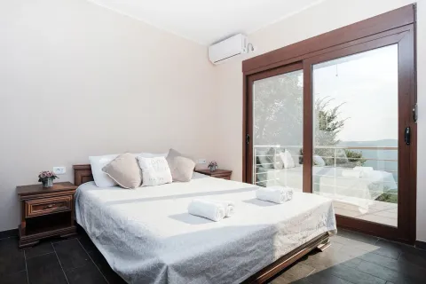 Bedroom with a double bed, nightstands, and large glass balcony doors. - image 11