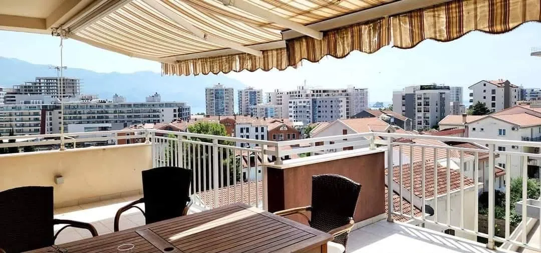 Furnished terrace with an awning and a view of the city and sea.