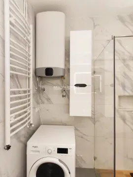 Bathroom with marble tiles, water heater, washing machine, and walk-in shower. - image 20