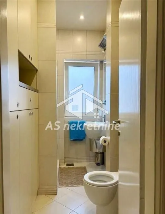 View of the bathroom with a sink, toilet, and built-in cabinets.