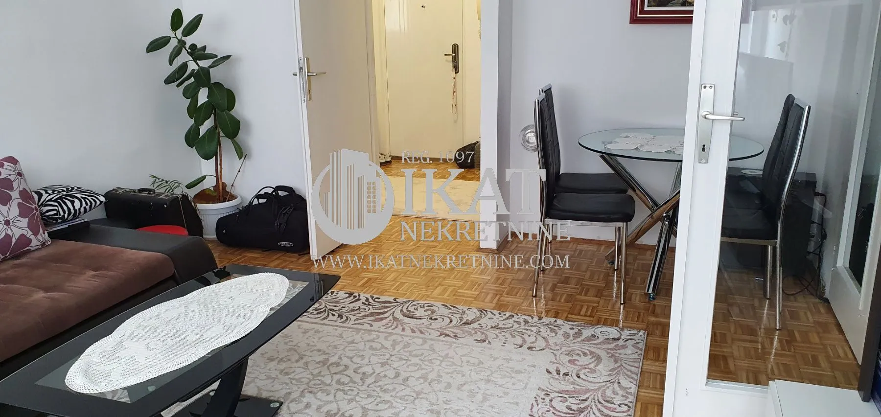 Living room with a sofa, dining table, and parquet flooring.