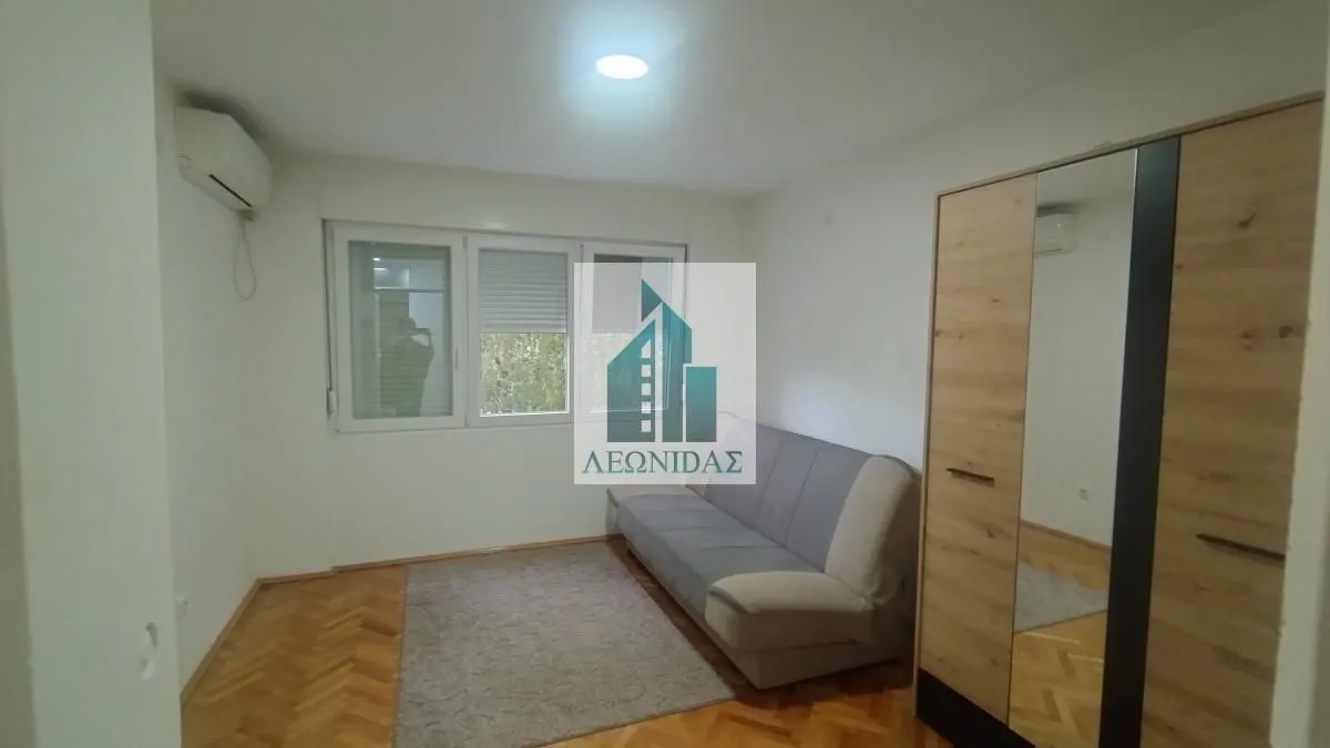 Living room with a sofa, wardrobe and wooden flooring.