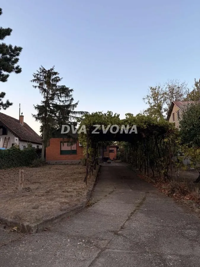 Pogled na dvorište i prilaz kuće sa senikom i travnjakom.