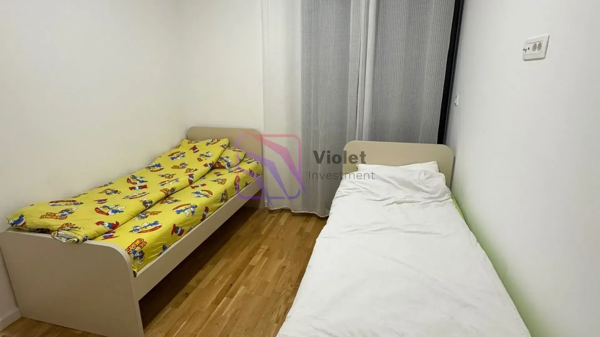 Bedroom with two single beds and wooden flooring.