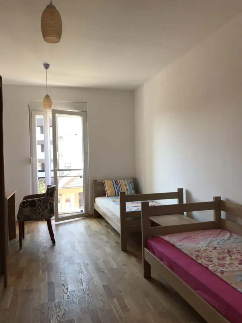 Bright bedroom with two single beds and balcony access.