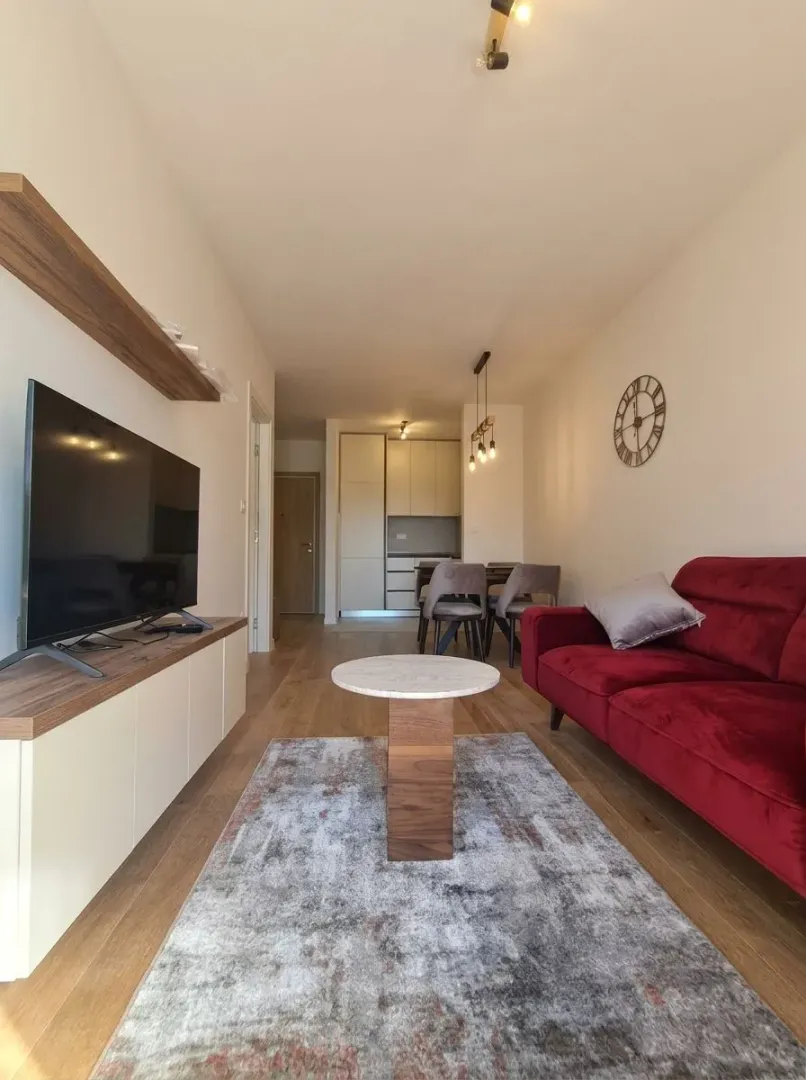 Living room with sofa, TV and dining area in the background.
