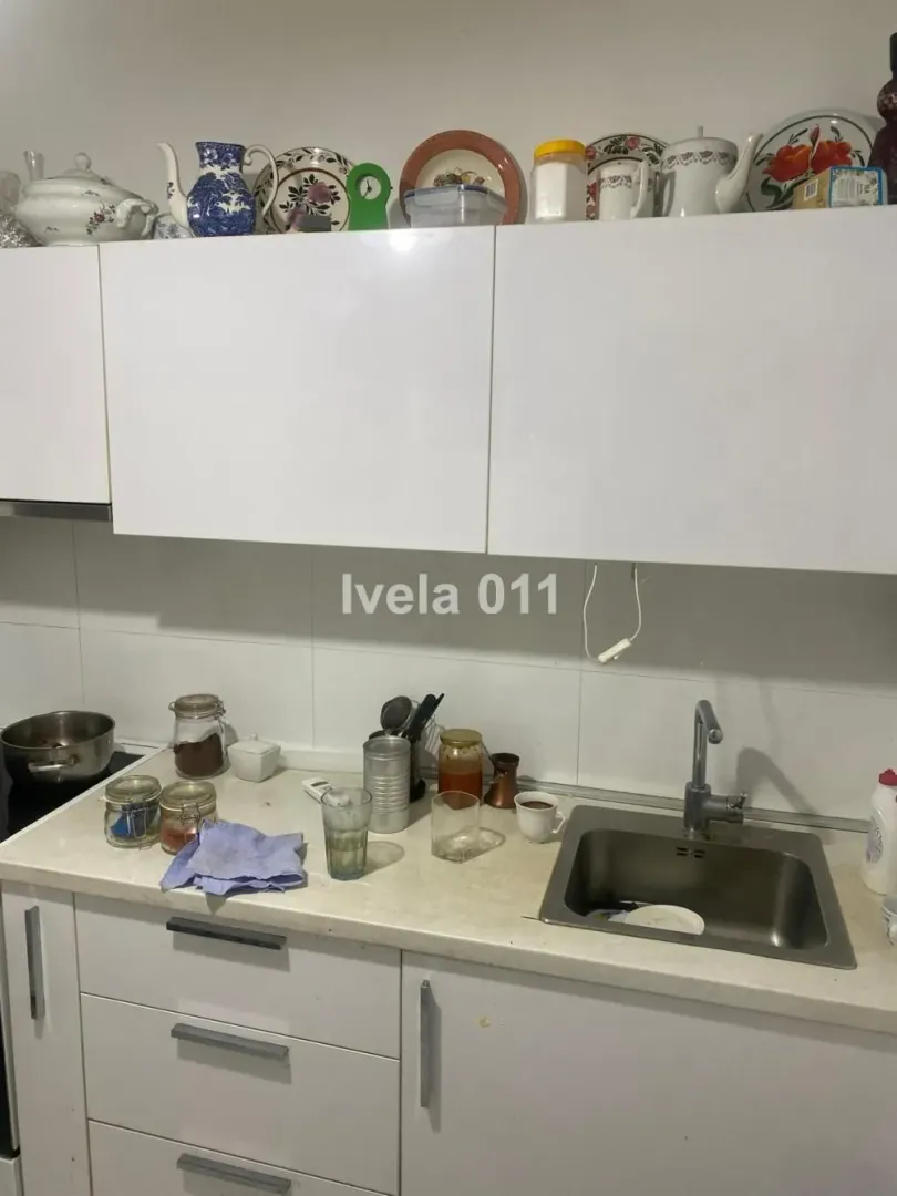 Dio kuhinje sa sudoperom, radnom površinom i visećim elementima.