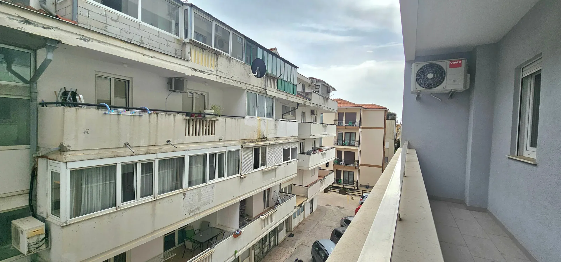 Pogled sa terase na okolne stambene zgrade i dvorište.
