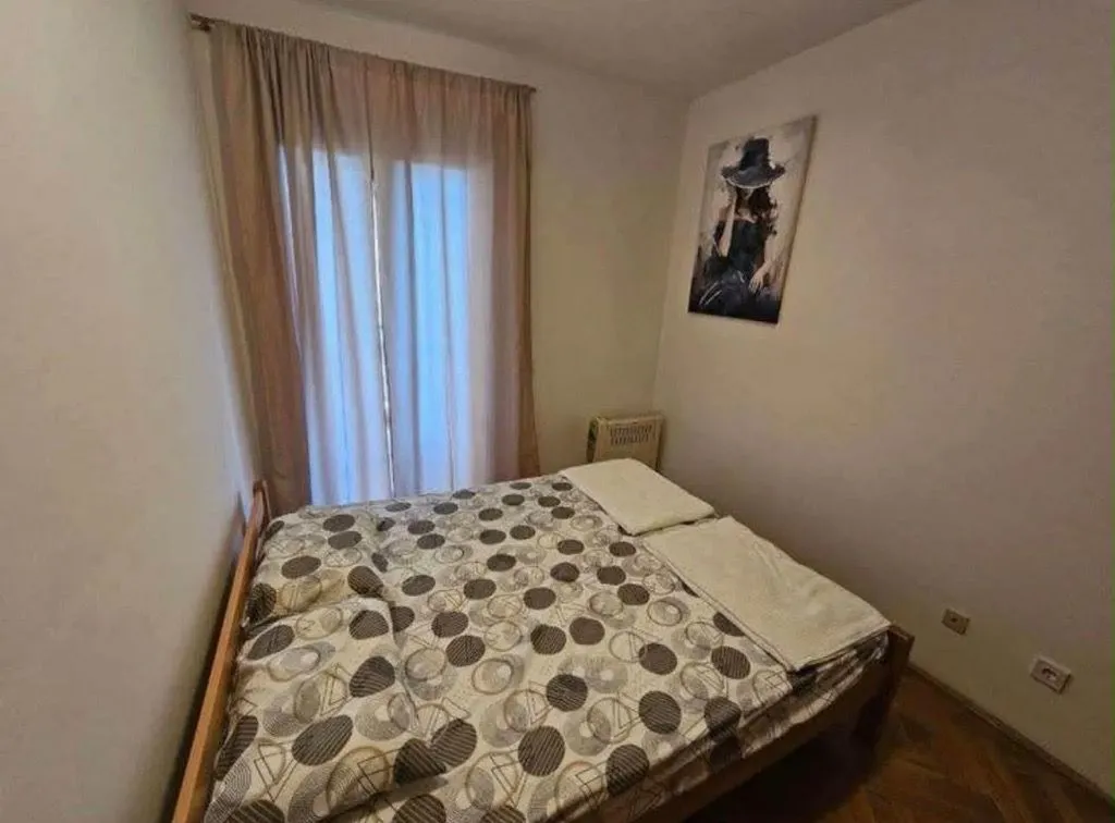 Namještena spavaća soba sa bračnim krevetom, prozorom i slikom na zidu.