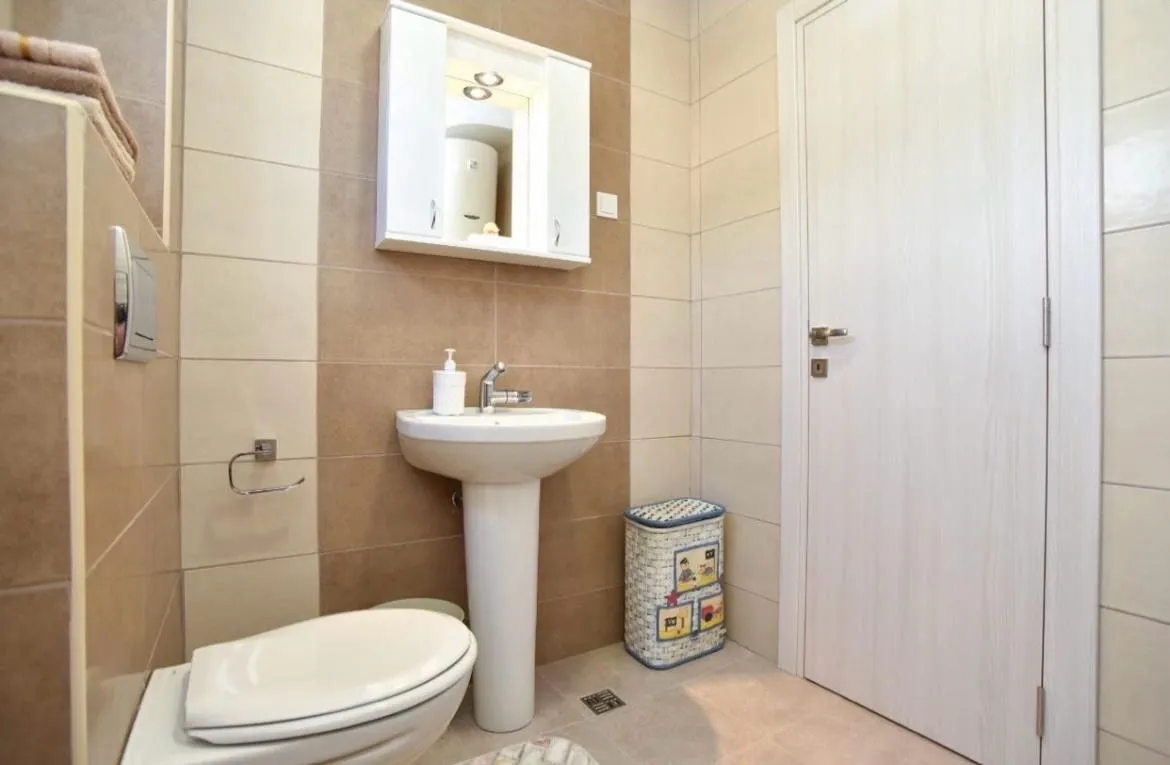 Compact bathroom with a sink, toilet, and mirrored cabinet.