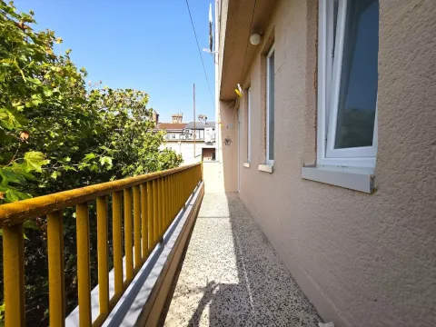 Long balcony with a yellow railing and a view of greenery and surrounding buildings. - image 15