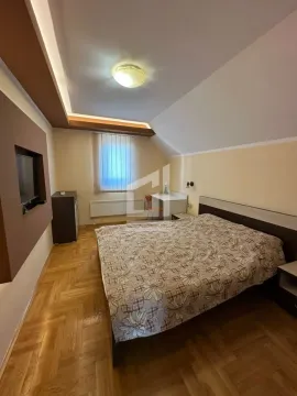 Namještena spavaća soba sa bračnim krevetom, radnim stolom i TV-om na zidu. - image 4