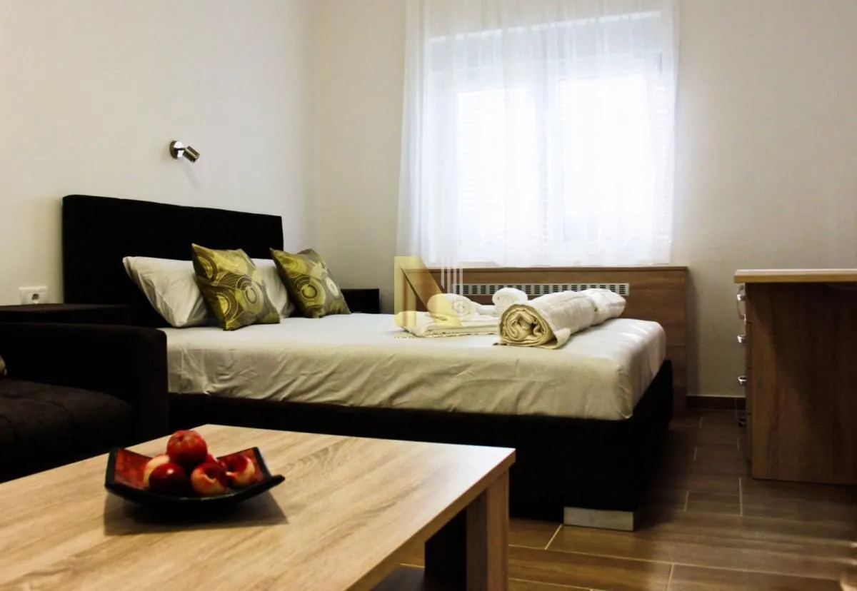 Bedroom with a double bed, rolled towels, and a wooden coffee table in the foreground.