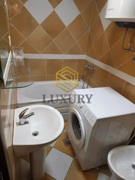 Smaller bathroom with a bathtub, washbasin, and washing machine. - image 6