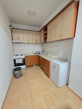 Smaller kitchen with wooden units, a stove, and a refrigerator. - image 11