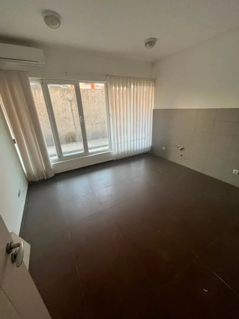Empty room with dark floor tiles and a window.