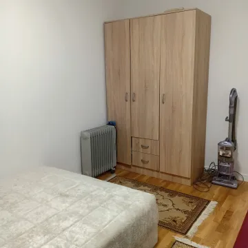 Manja spavaća soba sa krevetom, drvenim ormarom i radijatorom. - image 6