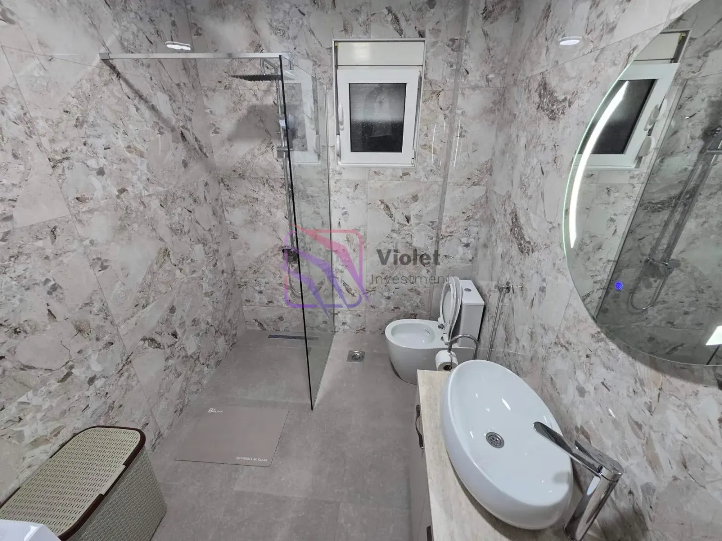 Modern bathroom with a walk-in shower, washbasin, and toilet.