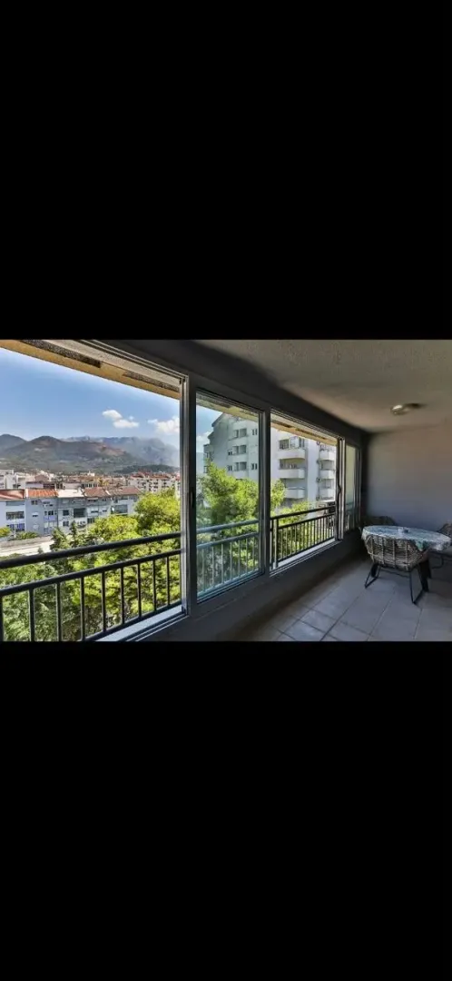 Enclosed balcony with a view of the city and mountains.