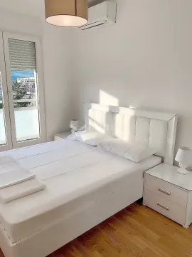 Svijetla spavaća soba sa bračnim krevetom, noćnim stočićima i izlazom na terasu. - image 7