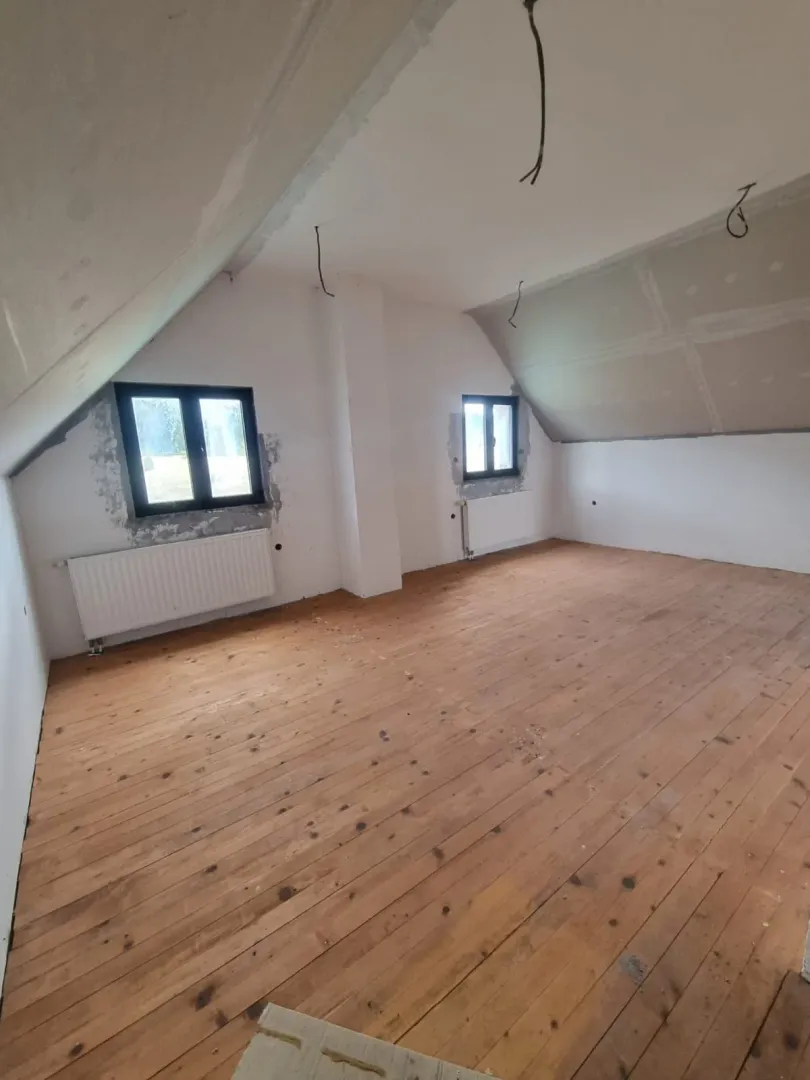 Nedovršena potkrovna prostorija sa drvenim podom.