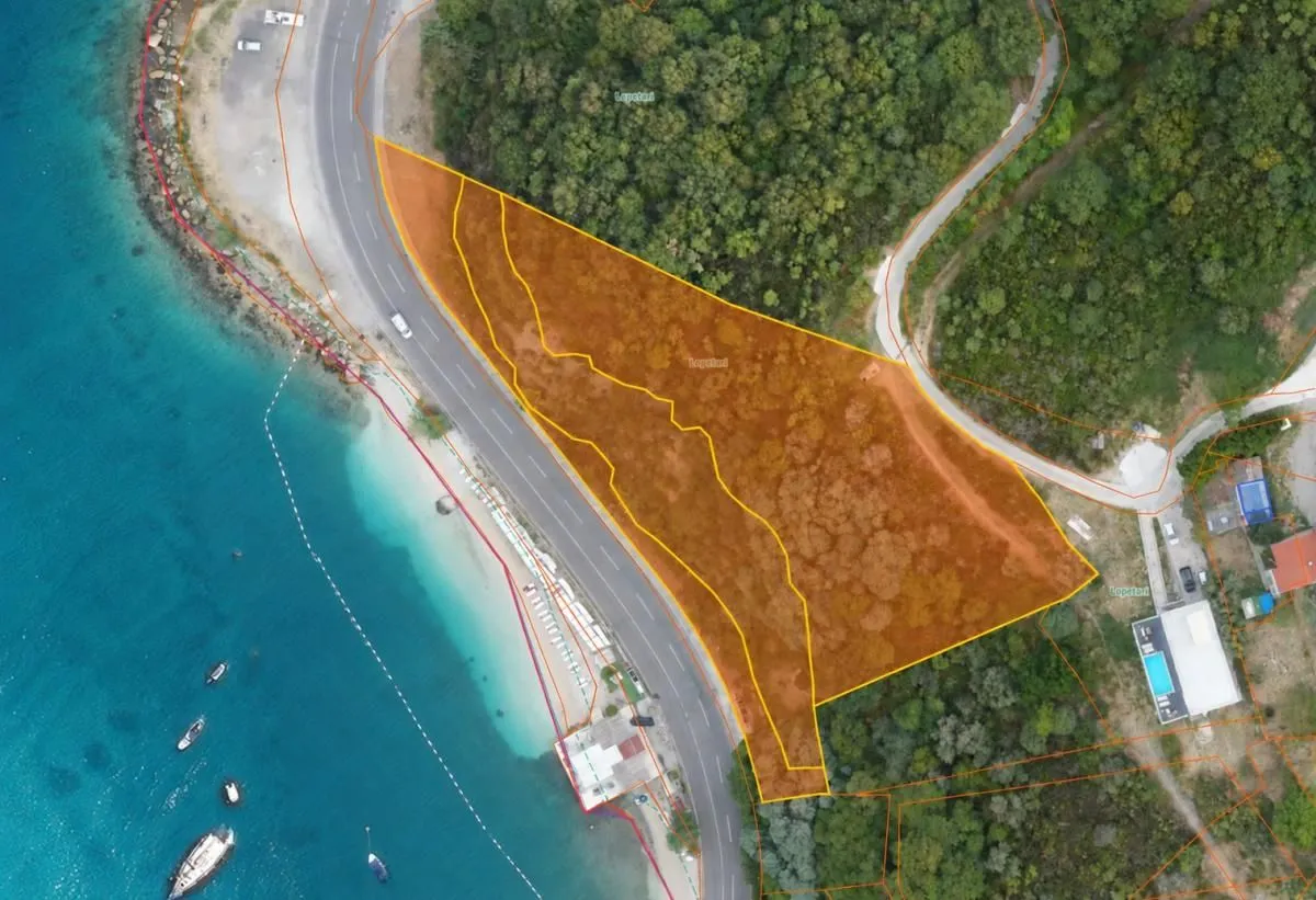Prikaz parcele sa ucrtanim granicama iz vazduha pored mora i puta.